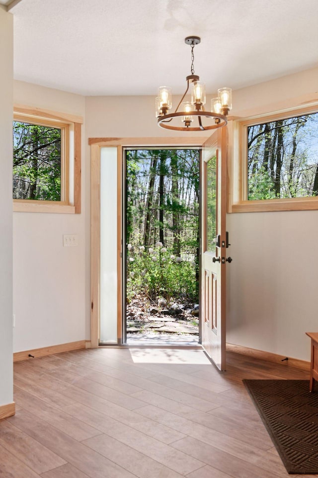 foyer with a chandelier, healthy amount of natural light, and light wood-style floors
