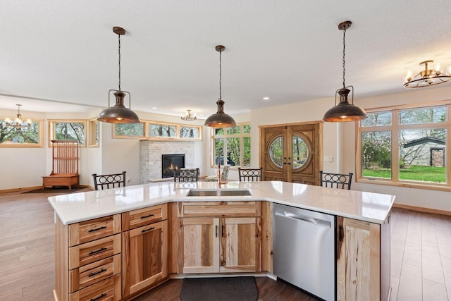 kitchen with stainless steel dishwasher, a sink, open floor plan, and a chandelier