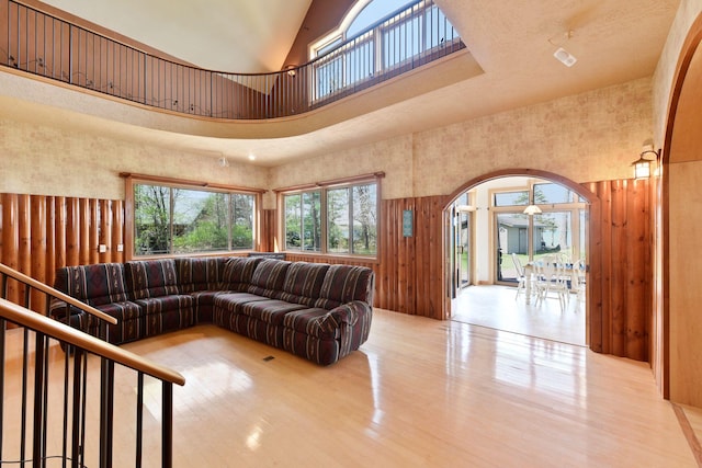 living area with a towering ceiling, arched walkways, and wood finished floors