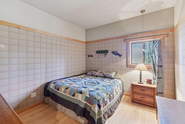 bedroom featuring tile walls and light wood finished floors