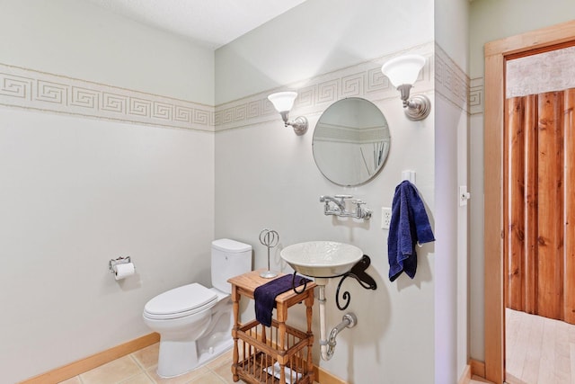 bathroom featuring toilet, baseboards, and tile patterned floors
