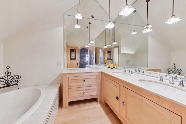 bathroom with double vanity, a bath, high vaulted ceiling, and wood finished floors