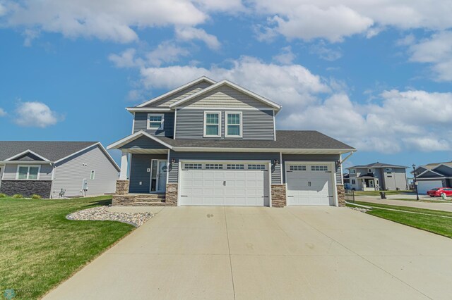 craftsman-style house with stone siding, driveway, a front lawn, and an attached garage