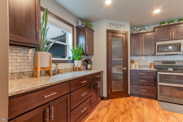 kitchen with stainless steel appliances, tasteful backsplash, light wood-style flooring, and light stone counters
