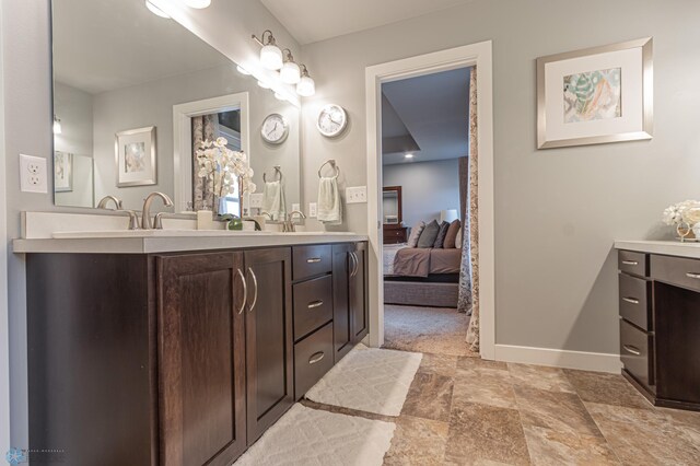 bathroom with double vanity, baseboards, stone finish flooring, and ensuite bath
