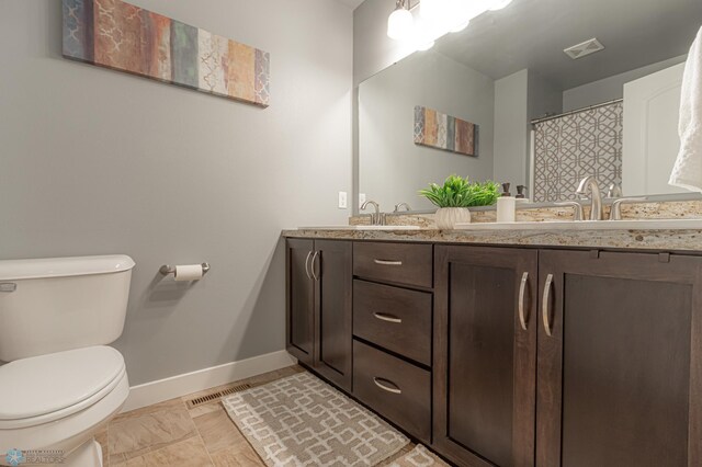 full bathroom featuring baseboards, toilet, and double vanity