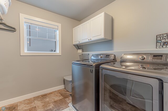 clothes washing area with cabinet space, washer and clothes dryer, baseboards, and light stone finish flooring