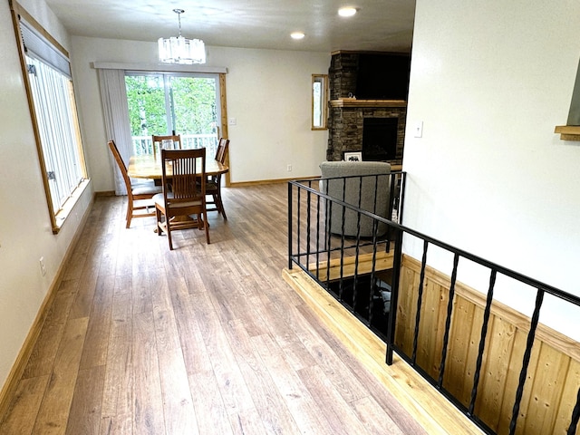 23479 State 200, Itasca Twp, MN 56676 - dining room featuring light wood-style flooring, a chandelier, baseboards, recessed lighting, and a stone fireplace