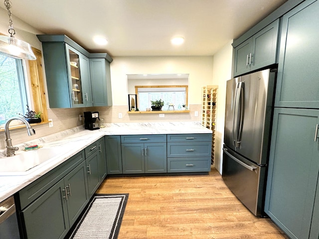 23479 State 200, Itasca Twp, MN 56676 - kitchen with freestanding refrigerator, a sink, glass insert cabinets, decorative light fixtures, and light wood finished floors