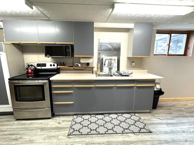 23479 State 200, Itasca Twp, MN 56676 - kitchen featuring stainless steel range with electric cooktop, black microwave, light wood finished floors, gray cabinets, and baseboards