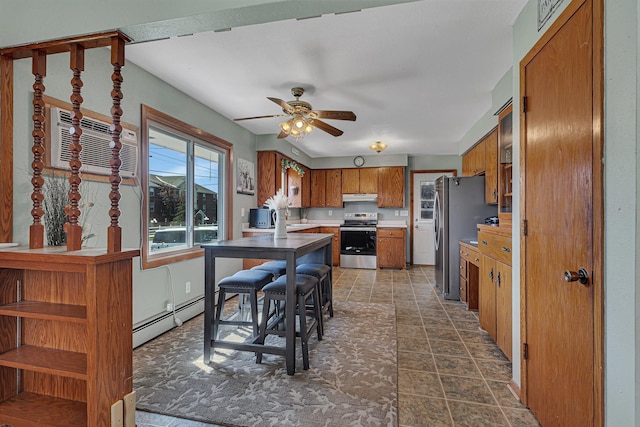 kitchen featuring appliances with stainless steel finishes, brown cabinetry, baseboard heating, a ceiling fan, and an AC wall unit