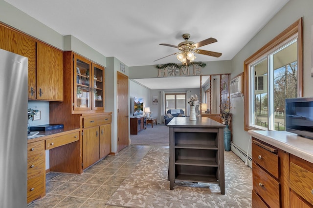 kitchen featuring open shelves, a ceiling fan, an office area, brown cabinets, and a baseboard heating unit