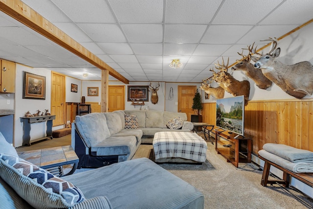 living area featuring a paneled ceiling and wooden walls