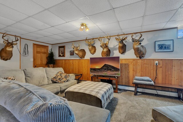 carpeted living room with a baseboard heating unit, a wainscoted wall, wooden walls, and a paneled ceiling