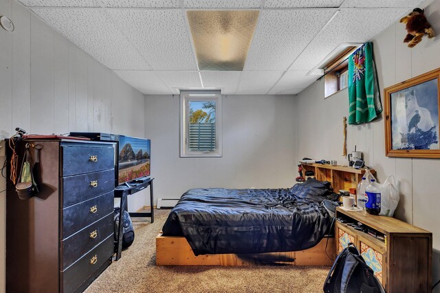 bedroom featuring multiple windows, carpet flooring, a drop ceiling, and a baseboard heating unit