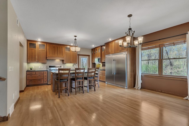 1901 11th St N, Sartell, MN 56377 - kitchen with built in appliances, brown cabinetry, baseboards, a breakfast bar area, and light wood-type flooring