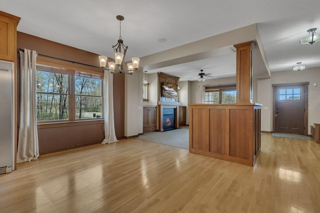 1901 11th St N, Sartell, MN 56377 - kitchen featuring brown cabinets, light wood-style flooring, a ceiling fan, and a glass covered fireplace