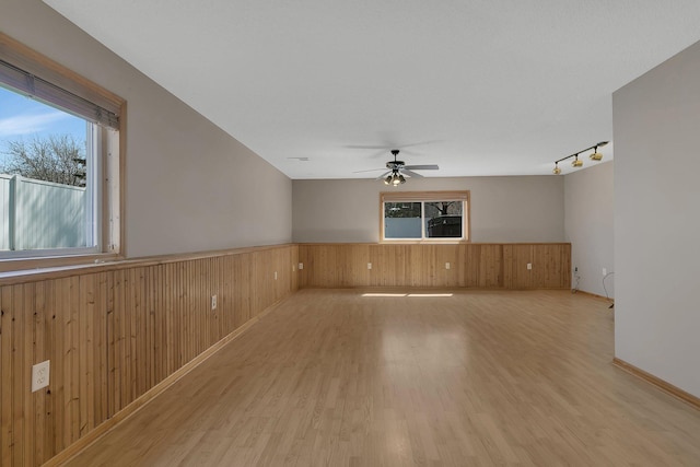 1908 5th St N, Sartell, MN 56377 - empty room with healthy amount of natural light, light wood finished floors, wooden walls, a wainscoted wall, and a ceiling fan
