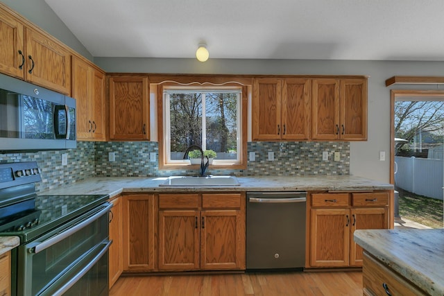 1908 5th St N, Sartell, MN 56377 - kitchen featuring stainless steel appliances, a sink, backsplash, light wood-style floors, and brown cabinets