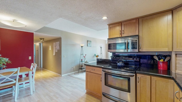kitchen with stainless steel appliances, a textured ceiling, dark countertops, light wood finished floors, and baseboards