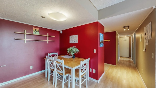 dining space featuring wood finished floors, a textured ceiling, crown molding, and baseboards