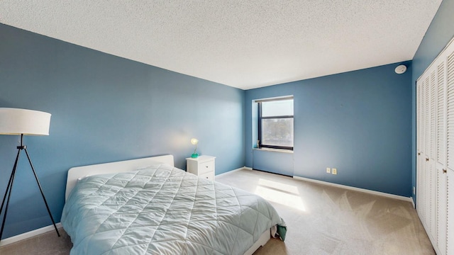 bedroom with carpet, baseboards, a textured ceiling, and a closet