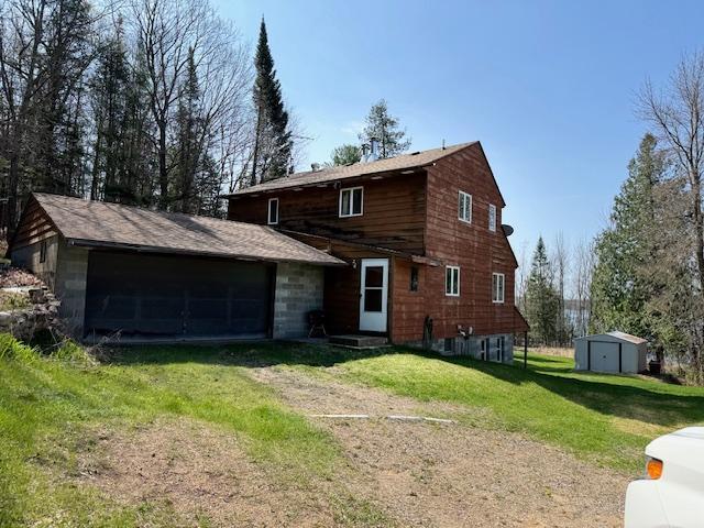 view of front of home featuring a storage shed, a front yard, an outdoor structure, and driveway