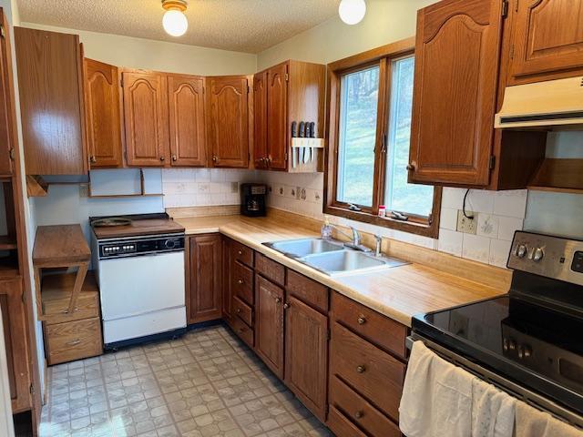 kitchen with stainless steel range with electric stovetop, a sink, extractor fan, light countertops, and light floors