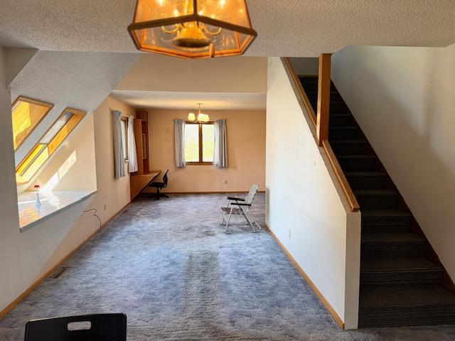 bonus room with a chandelier, carpet floors, stairway, a textured ceiling, and baseboards