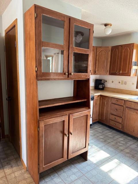 kitchen with light floors, brown cabinetry, and a textured ceiling