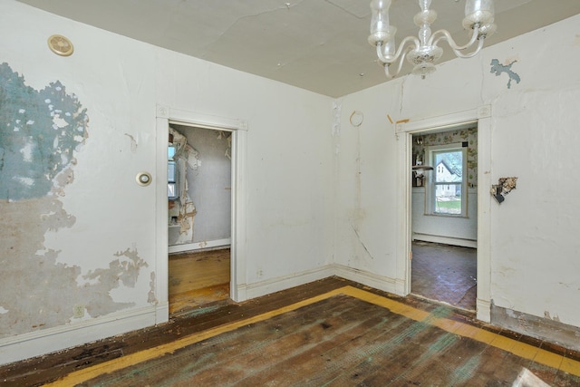414 4th St, Winthrop, MN 55396 - empty room featuring wood-type flooring, a chandelier, and baseboards
