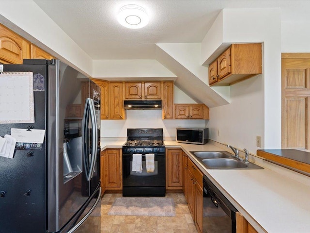 kitchen with black appliances, a sink, under cabinet range hood, and brown cabinetry