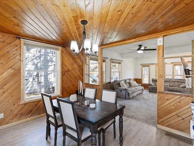 dining space with wooden ceiling, wood walls, a chandelier, wood finished floors, and baseboards