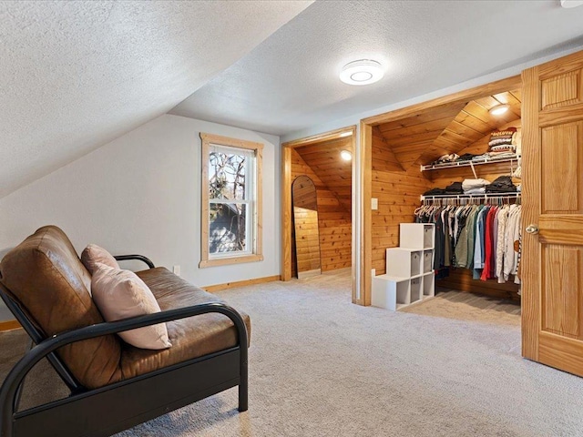 living area with carpet, a textured ceiling, baseboards, vaulted ceiling, and wood walls