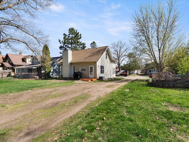 view of property exterior featuring driveway, a chimney, cooling unit, and a residential view