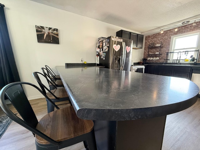 513 Water Ave N, Saint Hilaire, MN 56754 - dining room featuring light wood-style flooring, baseboards, rail lighting, and a textured ceiling