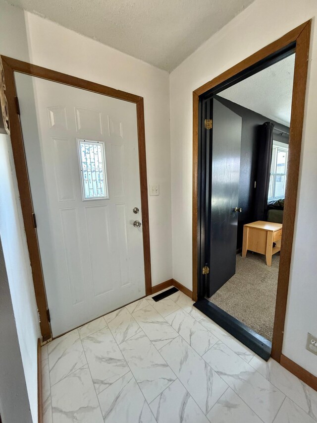 513 Water Ave N, Saint Hilaire, MN 56754 - foyer entrance featuring baseboards, light marble finish floors, and a textured ceiling