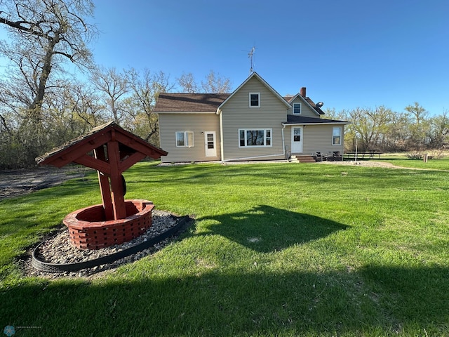 rear view of house with a chimney, a lawn, and entry steps