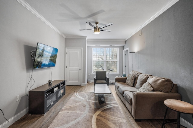 living room featuring wood finished floors, a ceiling fan, crown molding, and baseboards