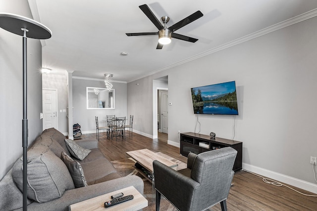 living area featuring wood finished floors, ornamental molding, ceiling fan, baseboards, and a chandelier