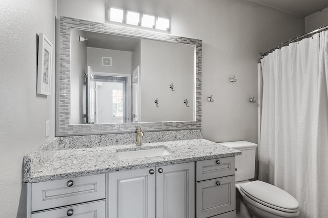 full bathroom featuring toilet, vanity, and tasteful backsplash