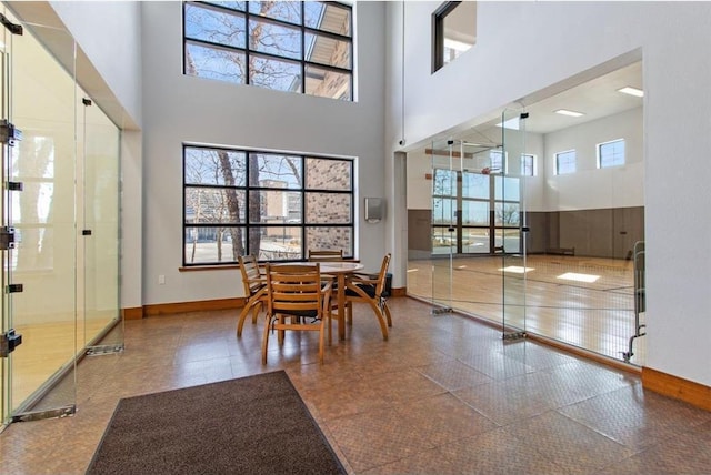 dining area featuring a towering ceiling and baseboards