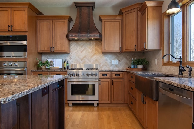 532 150th St, Alden Twp, WI 54001 - kitchen featuring stainless steel appliances, premium range hood, brown cabinetry, and light stone counters