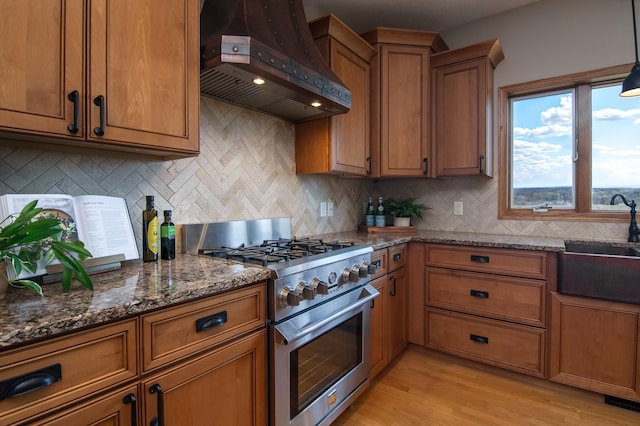 532 150th St, Alden Twp, WI 54001 - kitchen with high end stove, custom exhaust hood, brown cabinets, dark stone countertops, and tasteful backsplash