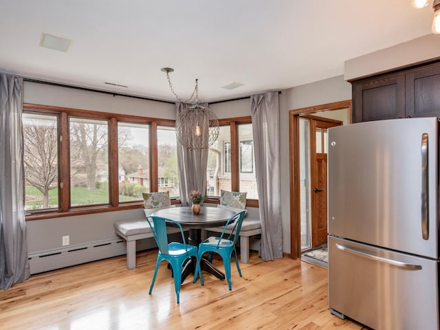 3509 Coolidge St NE, Saint Anthony, MN 55418 - dining area with a baseboard heating unit, a chandelier, healthy amount of natural light, and light wood-style flooring