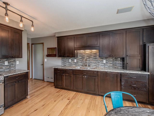 3509 Coolidge St NE, Saint Anthony, MN 55418 - kitchen with dark brown cabinets, tasteful backsplash, light wood-style flooring, light stone countertops, and a baseboard radiator
