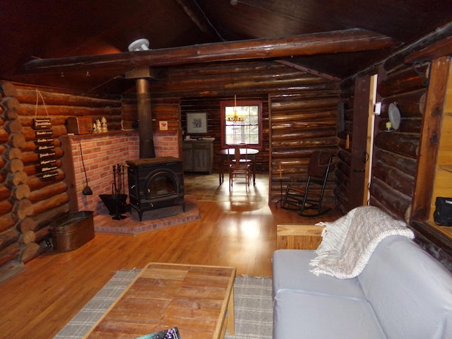 living area featuring log walls, wood finished floors, and a wood stove