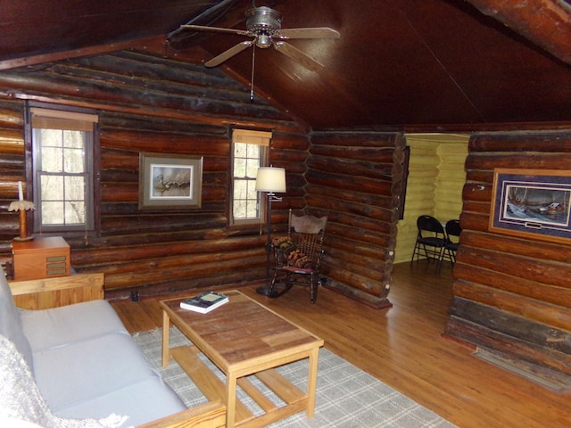 living room featuring a ceiling fan, lofted ceiling, wood finished floors, and rustic walls