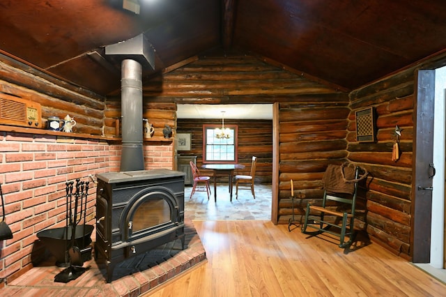 9262 Park Ave, Solon Springs, WI 54873 - living area featuring a wood stove, hardwood / wood-style floors, log walls, vaulted ceiling, and a chandelier
