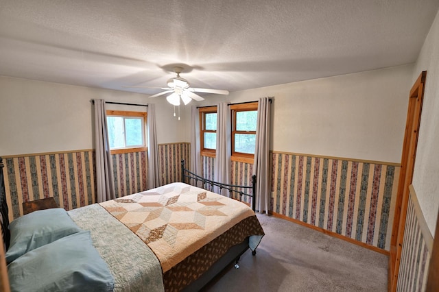 9262 Park Ave, Solon Springs, WI 54873 - carpeted bedroom featuring a wainscoted wall, wallpapered walls, a textured ceiling, and a ceiling fan